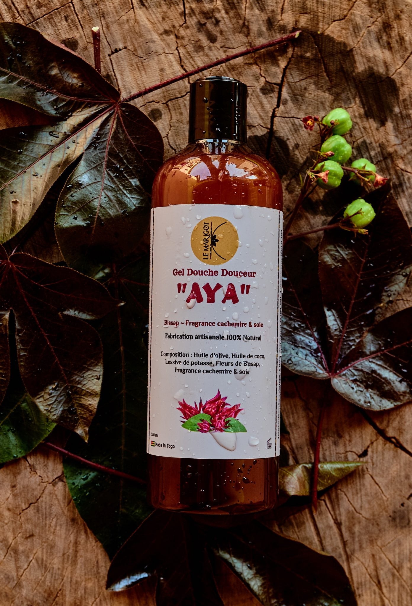 Flacon de soin artisanal AYA Le Marigot posé sur feuillage et bois, cosmétiques chez Asili